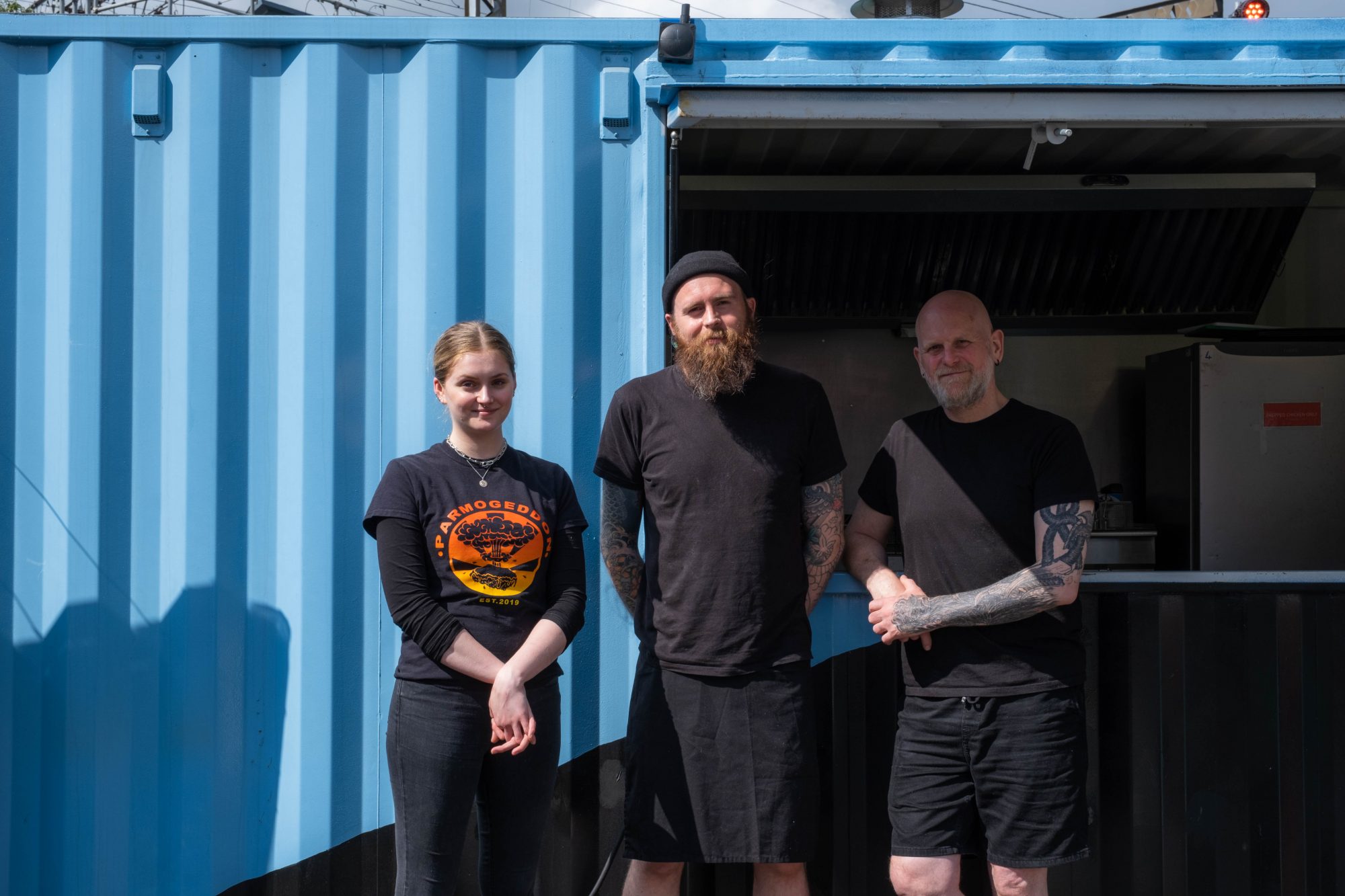 Image shows three people stood outside a storage container